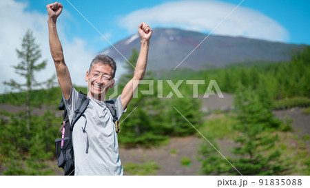 富士山をバックに手を挙げる登山者　 91835088