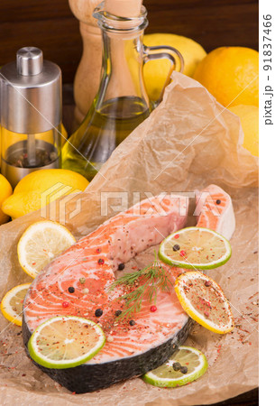Raw fish is ready for baking. Salmon steak. Red fish and sliced lemons on white Raw fish is ready for baking. Salmon steak. Red fish and sliced lemons on white 91837466