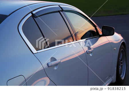乗用車のサイドウインドーとボディーに夕方の景色が映っている構図 乗用車のサイドウインドーとボディーに夕方の景色が映っている構図 91838215