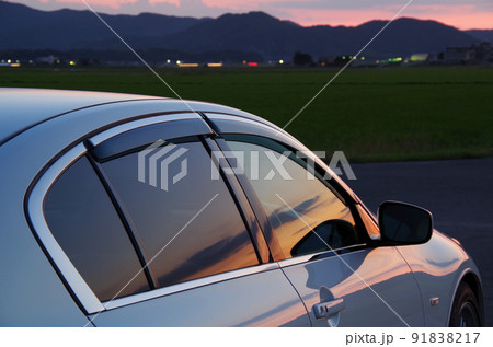 乗用車のサイドウインドーとボディーに夕方の景色が映っている構図 乗用車のサイドウインドーとボディーに夕方の景色が映っている構図 91838217