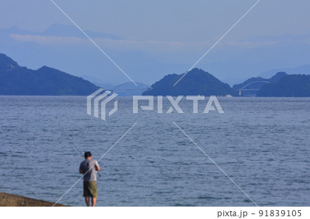 釣人の遠方に見える 県境に架かる橋と聳える瓶ヶ森 91839105