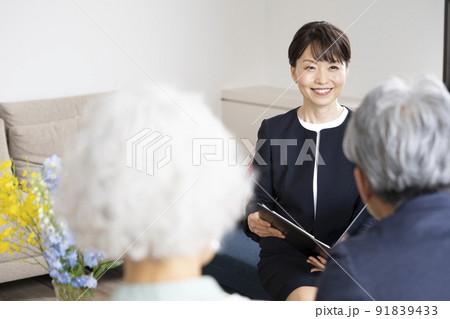 シニア夫婦に向かって話をするミドルのビジネスウーマン 91839433