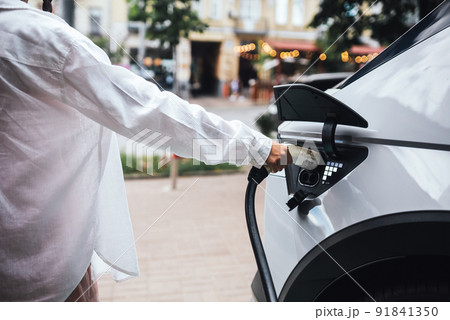 Human hand is holding Electric Car Charging nozzle. Human hand is holding Electric Car Charging nozzle. 91841350
