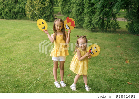 Winking, in love and tired, showing the tongue of a cardboard emoji in the hands of children 91841491