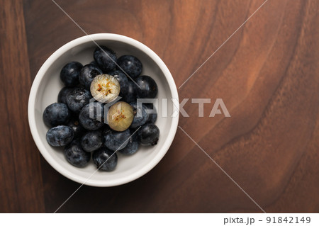Top view of ripe blueberries in a white bowl on wood table 91842149