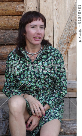 A girl in a green dress on the porch of a rustic wooden house A girl in a green dress on the porch of a rustic wooden house 91848781