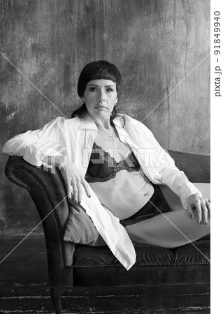 The girl is reclining on the sofa, sofa in an unbuttoned white shirt. 91849940