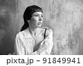 A girl with a sensual face and eyes in a white shirt and with a bare shoulder. 91849941