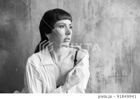 A girl with a sensual face and eyes in a white shirt and with a bare shoulder. 91849941