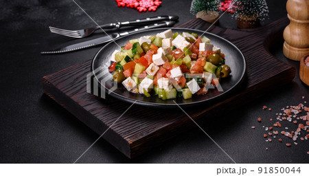 Greek salad with juicy tomatoes, feta cheese, lettuce, green olives, cucumber, red onion and fresh parsley 91850044
