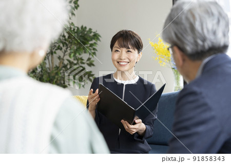 シニア夫婦に向かって話をするミドルのビジネスウーマン 91858343