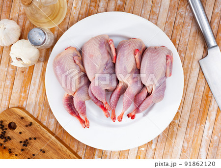 Raw gutted partridges on plate with seasonings on wooden table Raw gutted partridges on plate with seasonings on wooden table 91862120