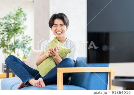 リビングでテレビを見る若い男性 91864016