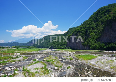 青空と夏雲を背景にした緑の七里岩と釜無川の流れ 91869701