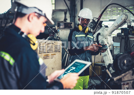 Factory workers working with adept robotic arm in a workshop Factory workers working with adept robotic arm in a workshop 91870507