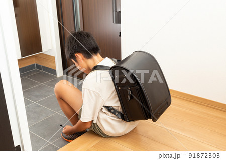 玄関で靴を履く小学生 91872303