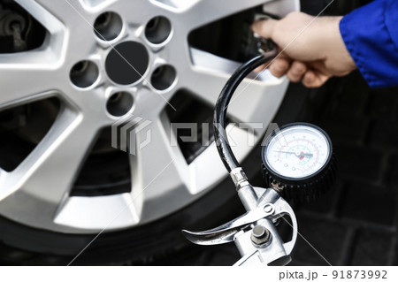 Mechanic checking tire air pressure at car service, closeup 91873992