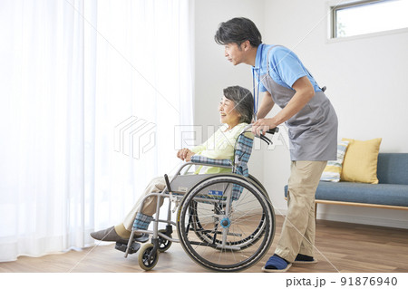 車椅子に座るシニアの女性とミドル男性の介護スタッフ 91876940