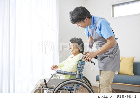 車椅子に座るシニアの女性とミドル男性の介護スタッフ 91876941