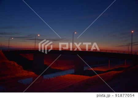 朝焼けとオレンジ色の街灯に照らされた橋 91877054