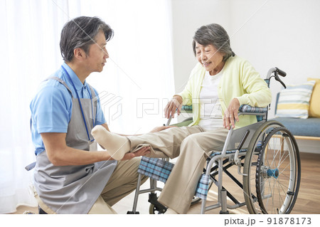 車椅子に座るシニアの女性とミドル男性の介護スタッフ 91878173