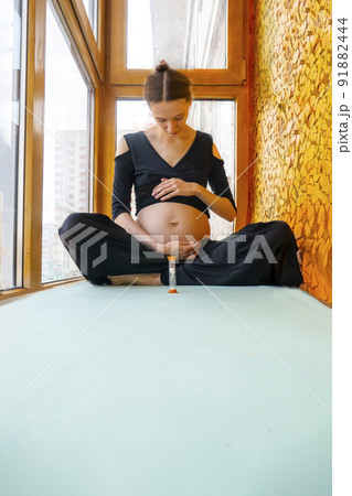 pregnant woman sitting and practicing yoga at home on the balcony pregnant woman sitting and practicing yoga at home on the balcony 91882444