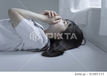 白い部屋で寝そべるセミロングの女子高校生 91885155