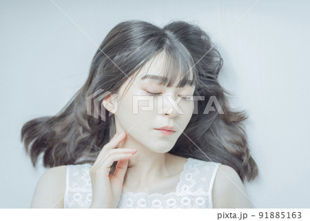 白い部屋で寝そべるセミロングの若い女性 91885163