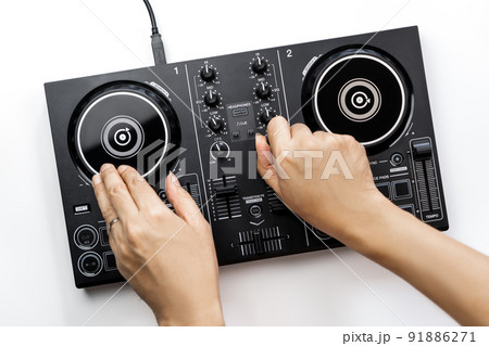 DJ hands is mixing music on DJ Digital mixing controller top view on white background. 91886271
