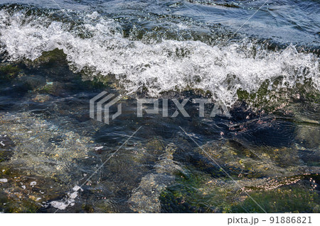 Sea waves crash against large rocks on the shore, forming large splashes Sea waves crash against large rocks on the shore, forming large splashes 91886821