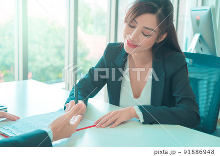 Female job canidate is signing work contract with HR officer after a sucessful job interview. Female job canidate is signing work contract with HR officer after a sucessful job interview. 91886948