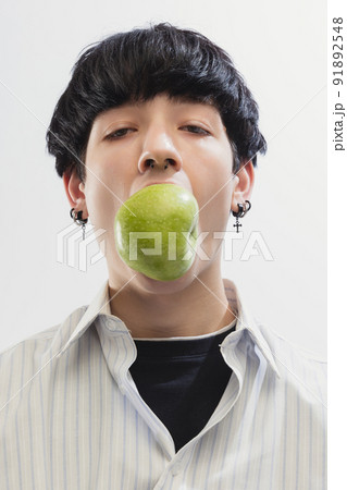 Portrait of young man in shirt posing with apple isolated over grey studio background Portrait of young man in shirt posing with apple isolated over grey studio background 91892548