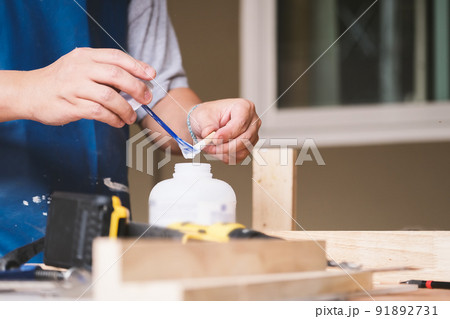 Woodworking operators are using glue to put together the wood parts to assemble and build a wooden table for their customers 91892731