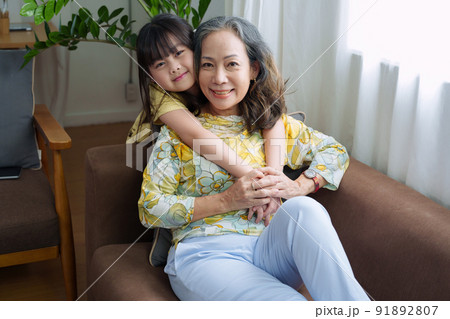 Asian portrait, grandma and granddaughter doing leisure activities and hugging to show their love and care for each other. 91892807