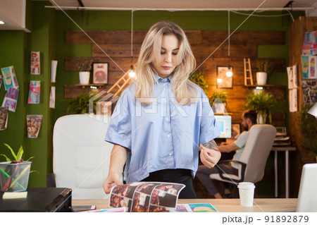 Creative female designer in her office with coworker in the background. 91892879