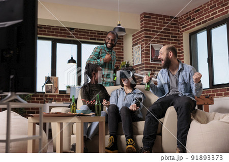Diverse group of friends celebrating video games victory, winning game with augmented reality goggles on tv console. People using vr glasses to win competition at house party, leisure activity. 91893373