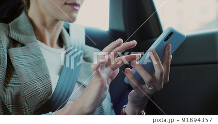 Closeup of woman hands texting and using smartphone device in back seat car. 91894357