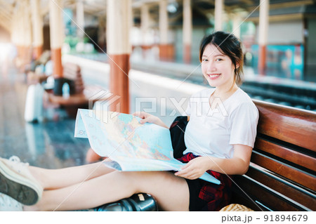 summer, relax, vacation, travel, portrait of a cute Asian girl looking at a map to plan a trip while waiting at the train station summer, relax, vacation, travel, portrait of a cute Asian girl looking at a map to plan a trip while waiting at the train station 91894679