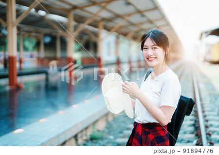 summer, relax, vacation, travel, portrait of cute Asian girl showing smile and showing joy while waiting at the train station for a summer trip summer, relax, vacation, travel, portrait of cute Asian girl showing smile and showing joy while waiting at the train station for a summer trip 91894776