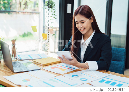 financial, Planning, Marketing and Accounting, portrait of Asian woman Economist using calculator to calculate investment documents with partners on profit taking to compete with other companies. 91894954