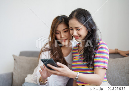lgbtq, lgbt concept, homosexuality, portrait of two asian women enjoying together and showing love for each other while using smartphone mobile to take selfies. 91895035
