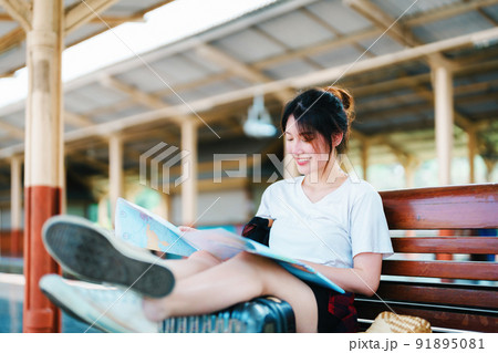 summer, relax, vacation, travel, portrait of a cute Asian girl looking at a map to plan a trip while waiting at the train station summer, relax, vacation, travel, portrait of a cute Asian girl looking at a map to plan a trip while waiting at the train station 91895081