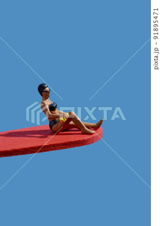 miniature woman sitting on a yellow diving board miniature woman sitting on a yellow diving board 91895471