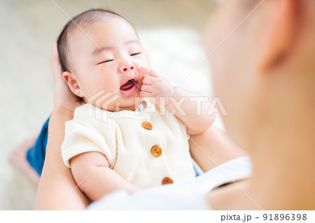 ママの膝の上でのふれあい　自分の顔を触る生後2ヶ月の赤ちゃん　指差す 91896398