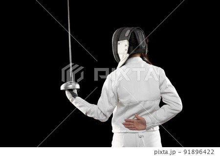 One sportsman, female fencer in white fencing costume in action, motion isolated on black background. Sport, youth, hobbies, achievements, goal. 91896422