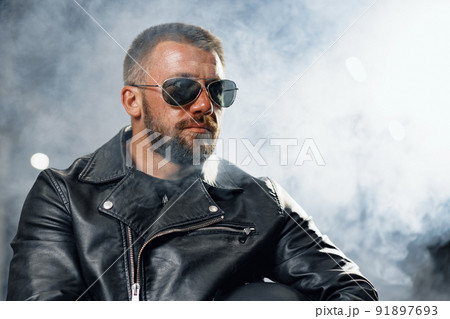 Portrait of bearded man motocyclist in dark sunglasses on dark background 91897693