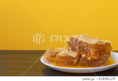 Honeycombs in white plate on the wooden table. Natural organic bee product. Healthy lifestyle. Copy space for your text. Close-up photo. 91898124