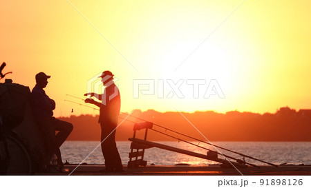 Silhouette of fishermen on the pier at sunset 91898126