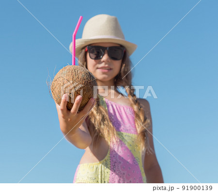 Girl Stretches out her hand with a coconut and a tube against the background of the sky Girl Stretches out her hand with a coconut and a tube against the background of the sky 91900139