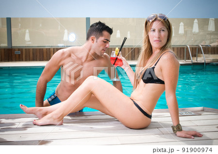 couple having a cocktail by the pool while enjoying the sun in spring or summer couple having a cocktail by the pool while enjoying the sun in spring or summer 91900974